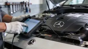 Mechanic using diagnostic tablet on Mercedes engine