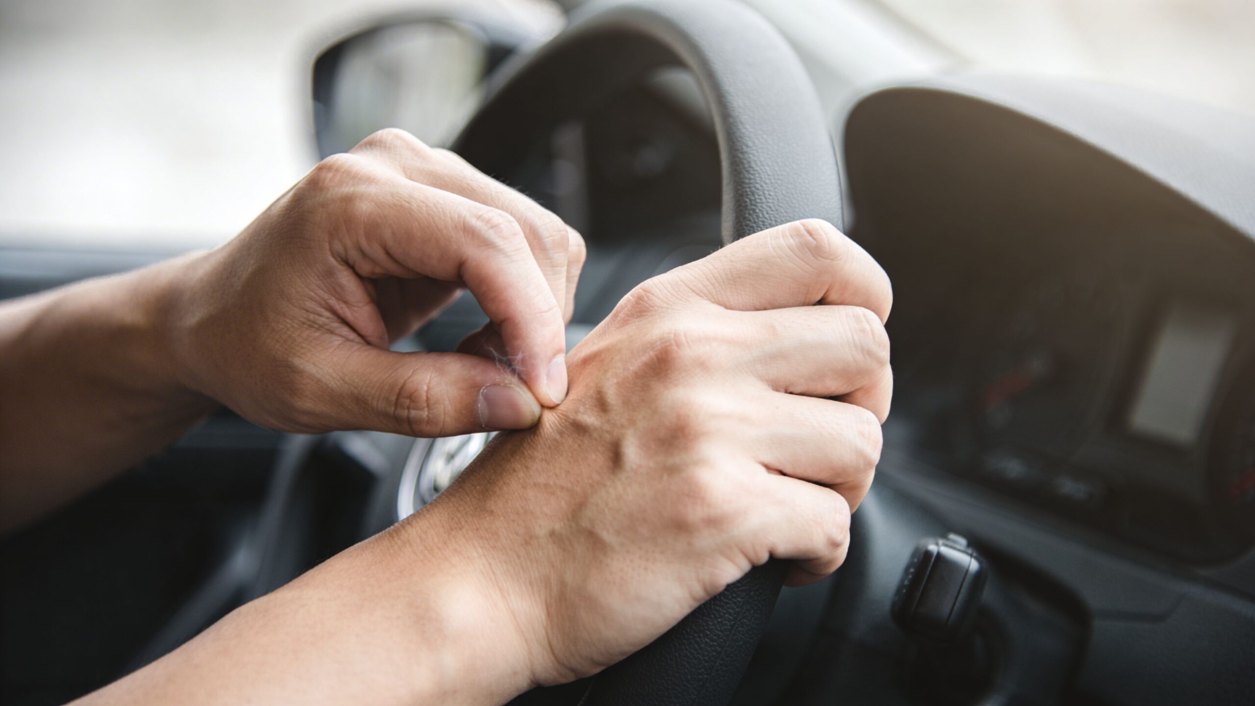A close-up view of a driver hands gripping the steering wheel while driving a car.