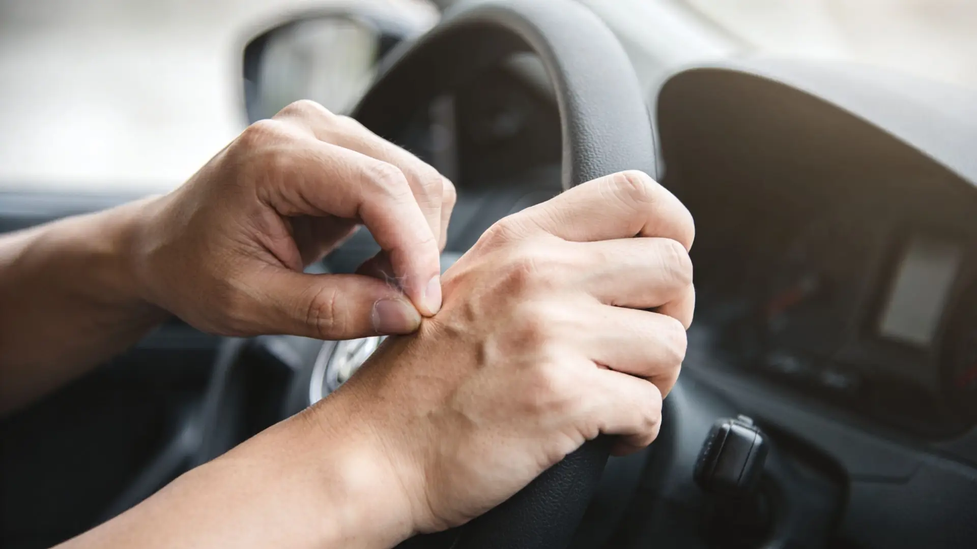 A close-up view of a driver hands gripping the steering wheel while driving a car.