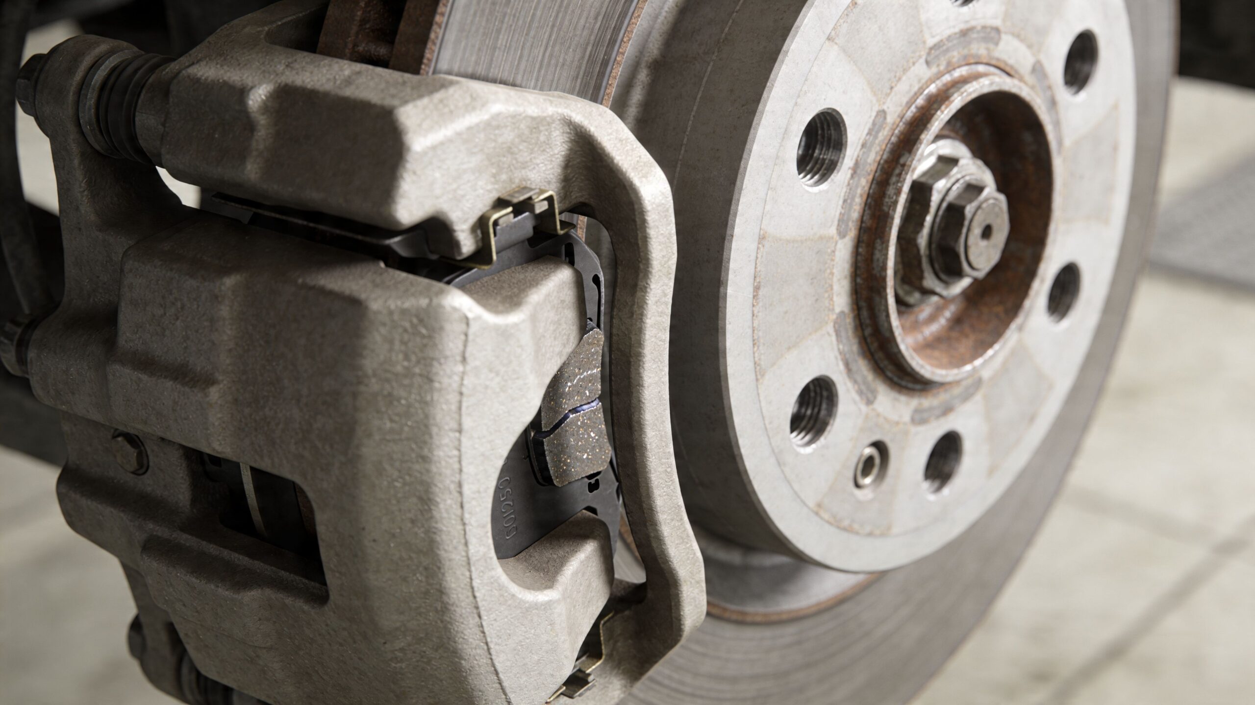 Close up view of a car disc brake system with a new brake pad installed on a rotor.