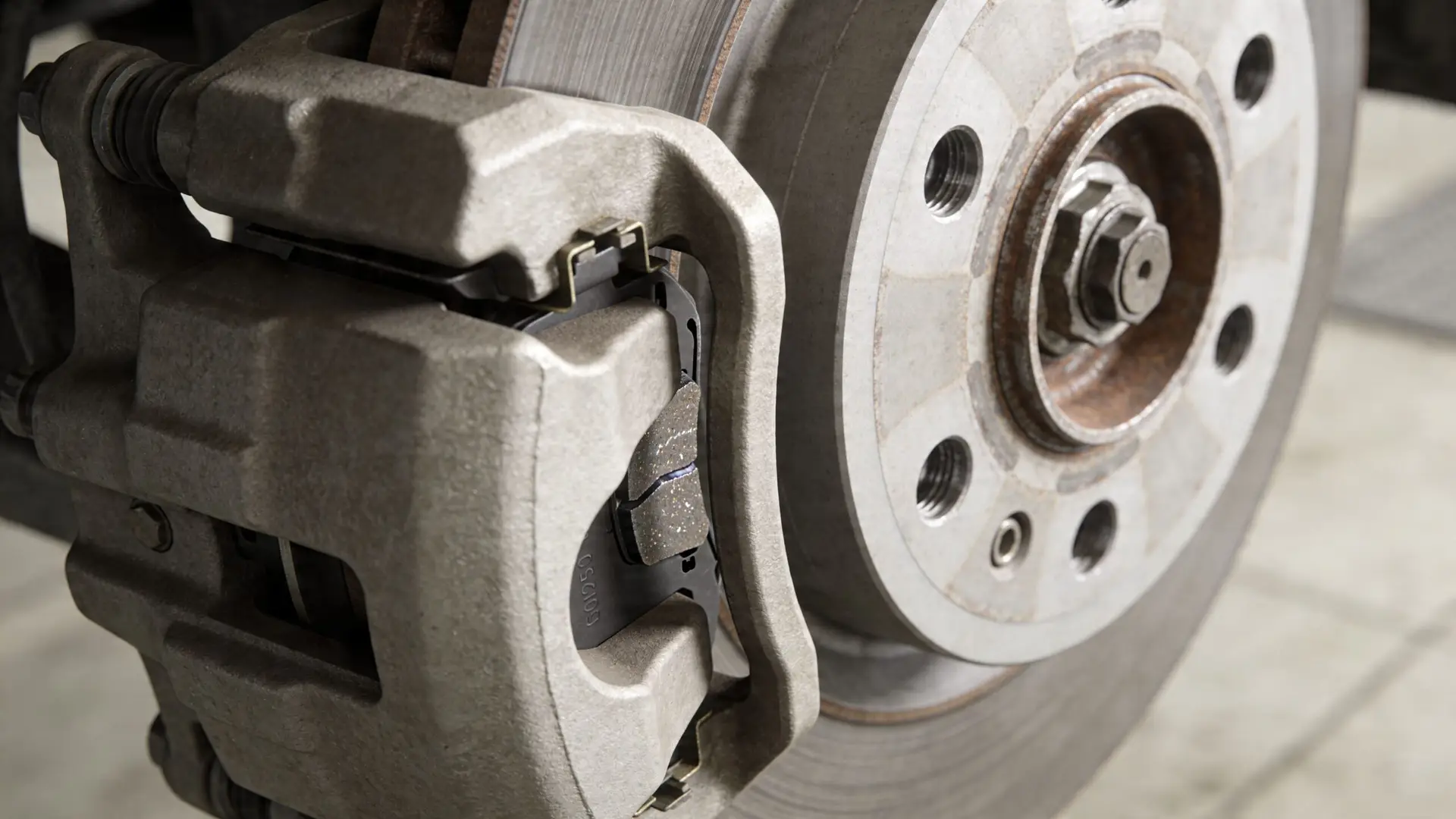 Close up view of a car disc brake system with a new brake pad installed on a rotor.