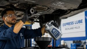Mechanic changing oil under Hyundai Tucson SUV