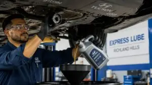Mechanic changing oil under Hyundai Tucson SUV