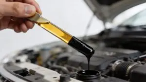 Hand holding dipstick with dirty engine oil