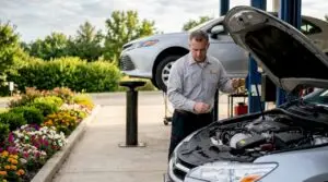 Technician checking oil level on car outdoors