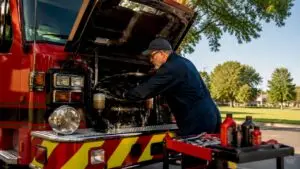 Mechanic inspecting fire truck engine in garage