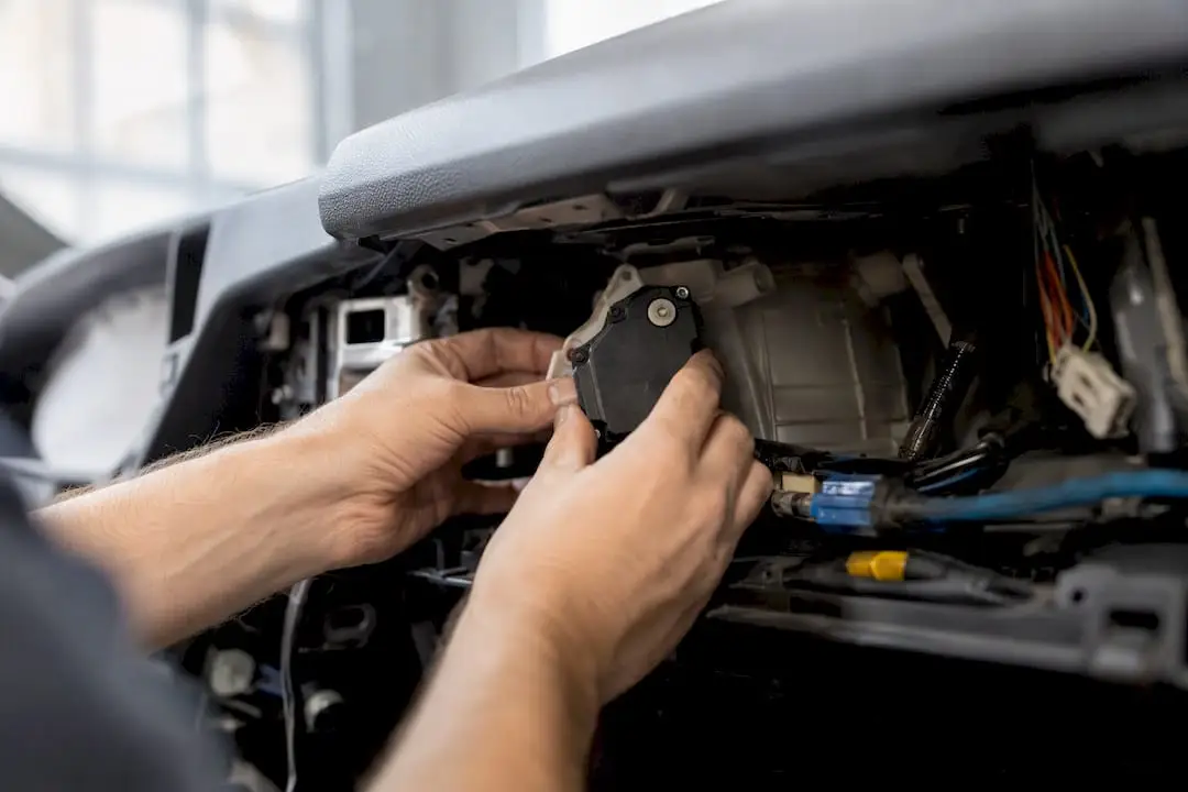 Hands repairing blend door actuator behind dashboard