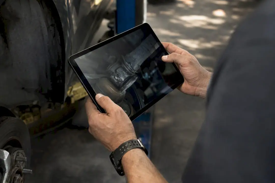 Technician holding tablet showing vehicle inspection photo