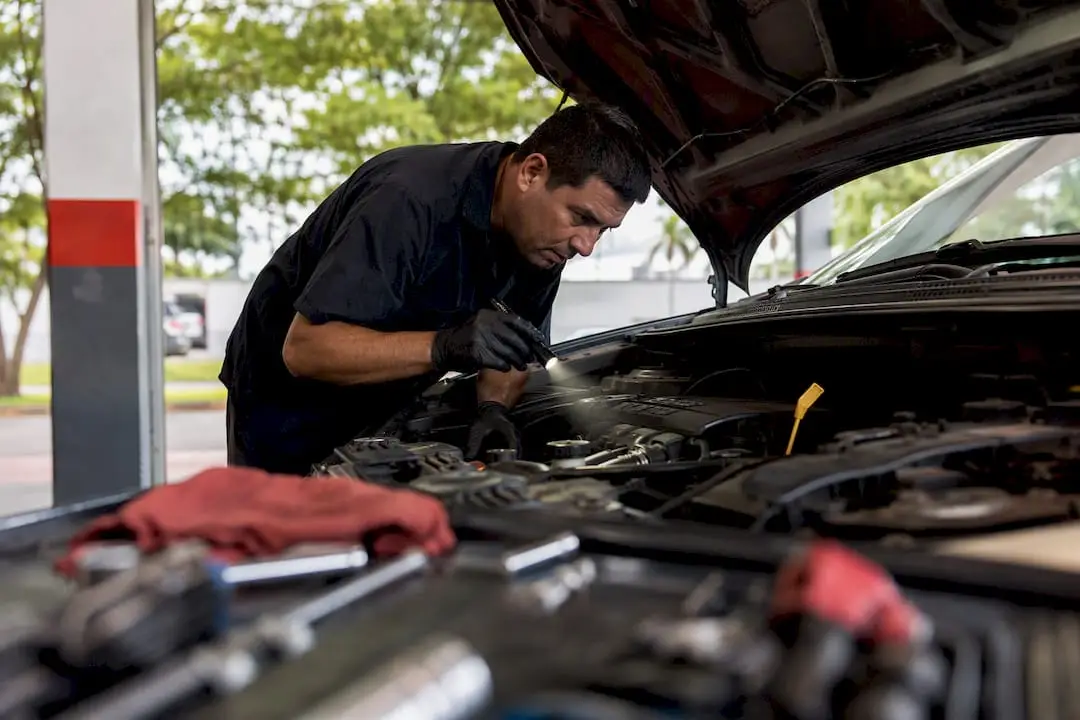 Technician inspecting vehicle engine with flashlight