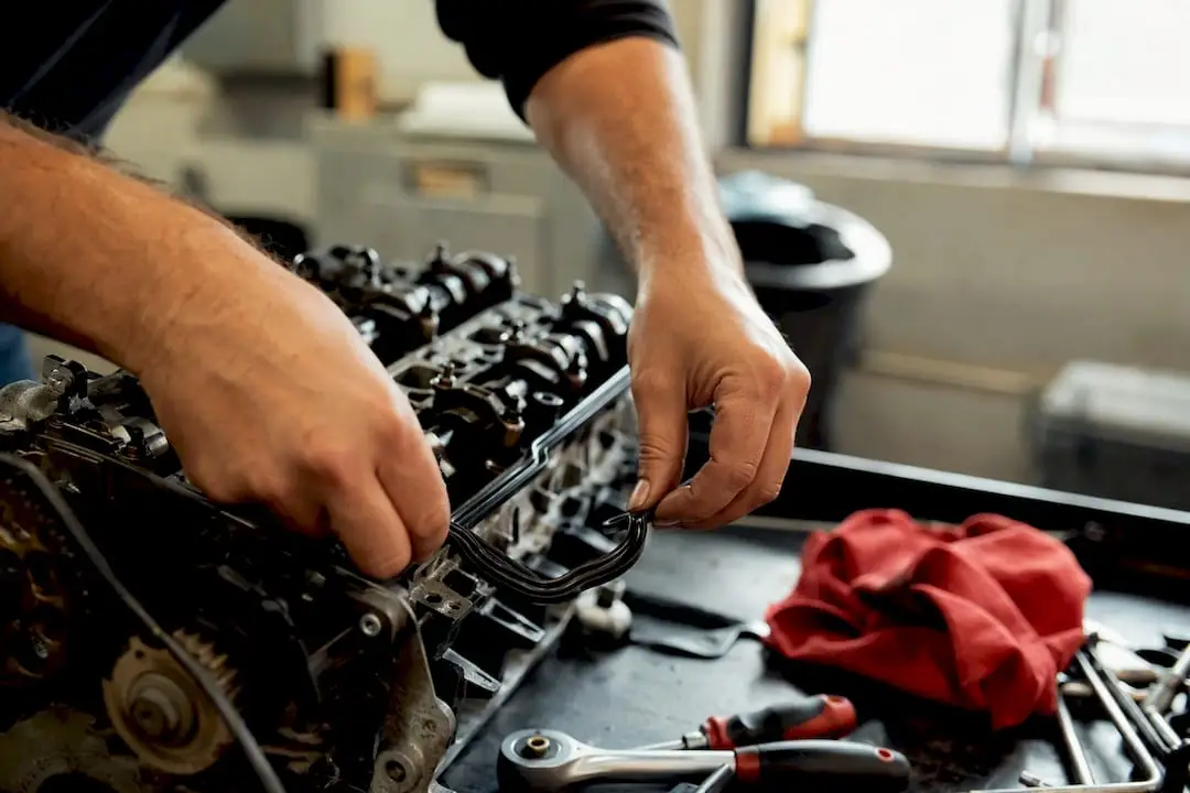 Hands replacing valve cover gasket in engine bay