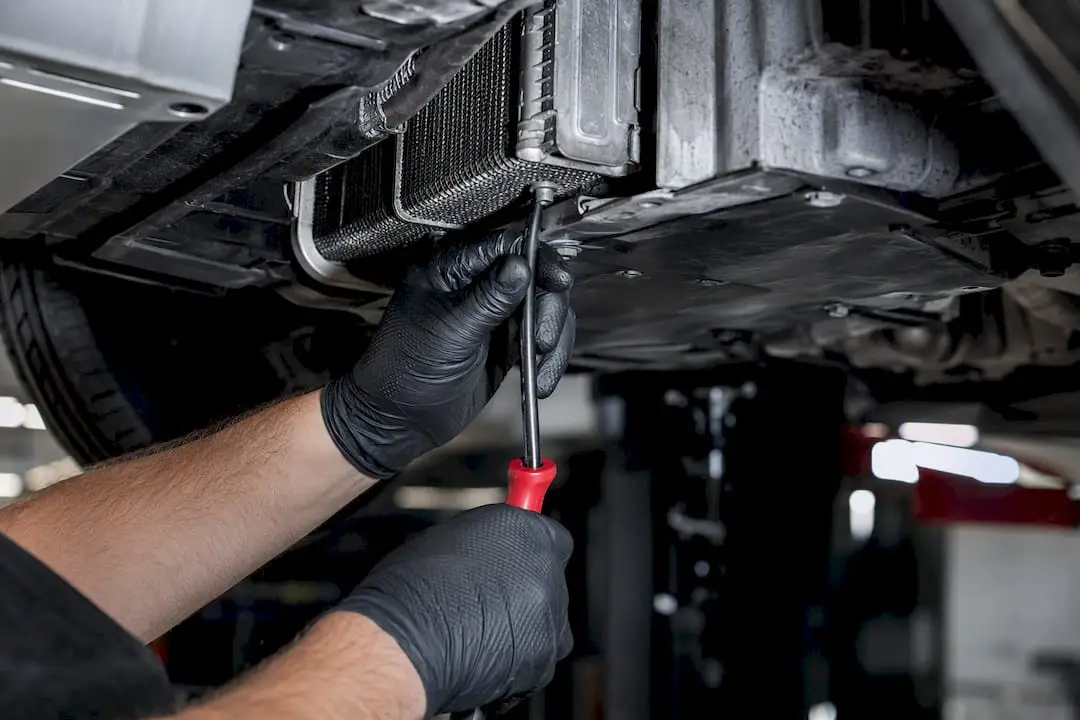 Technician cleaning a vehicle AC drain tube