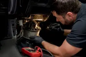 Technician inspecting a vehicle blower motor